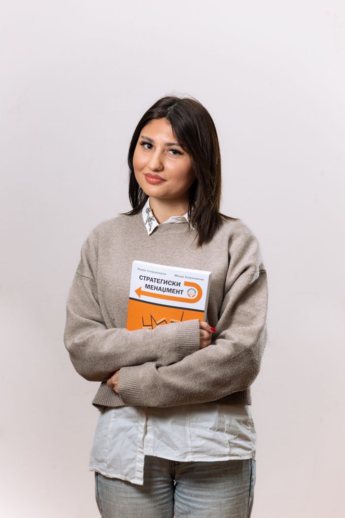 The Art of Drawing Readers In: Your attractive post title goes here Confident woman holding a strategic management book in a studio setting, showcasing professional style.